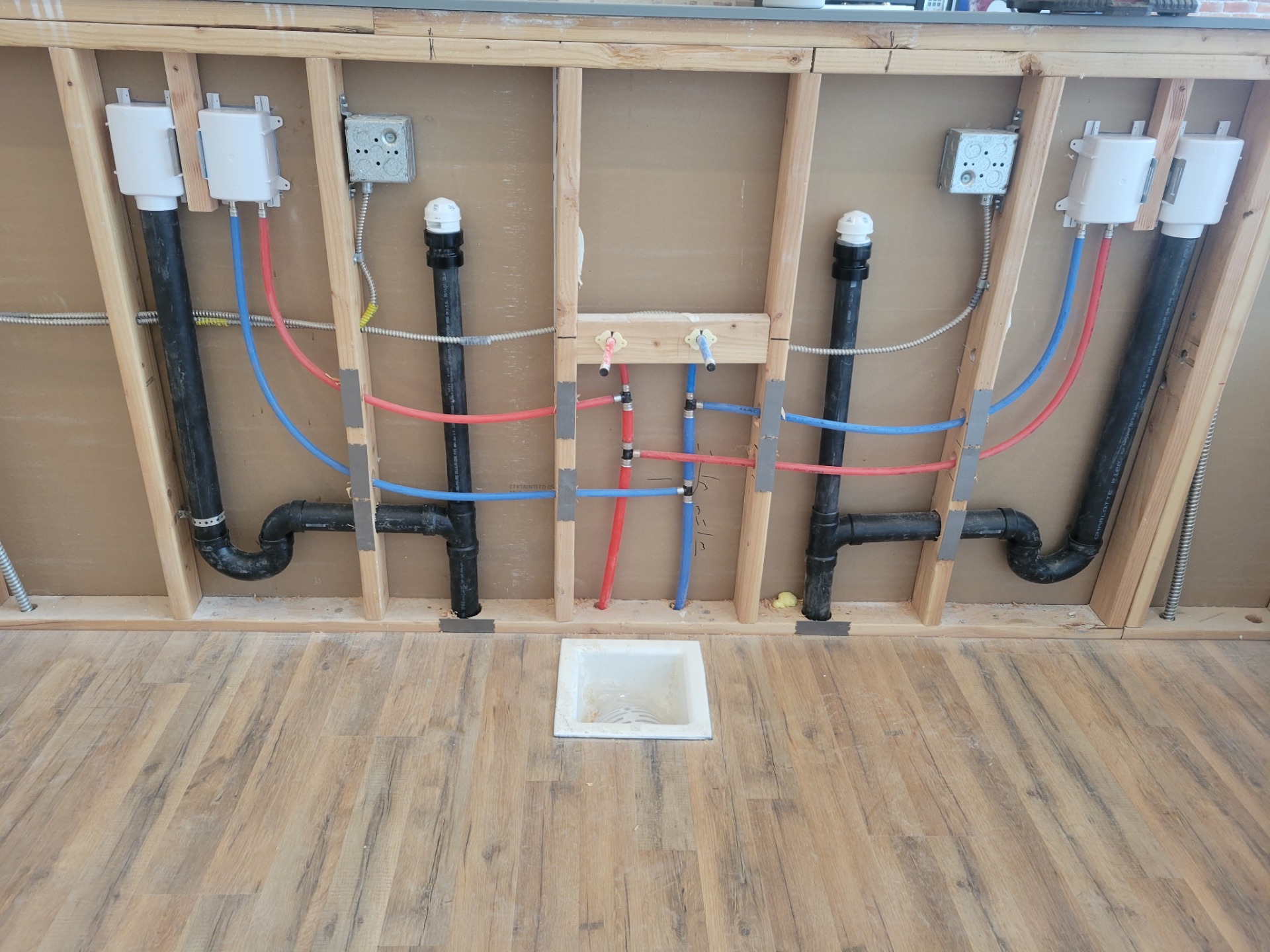 Multi-fixture restroom rough-in with carrier-mounted drains